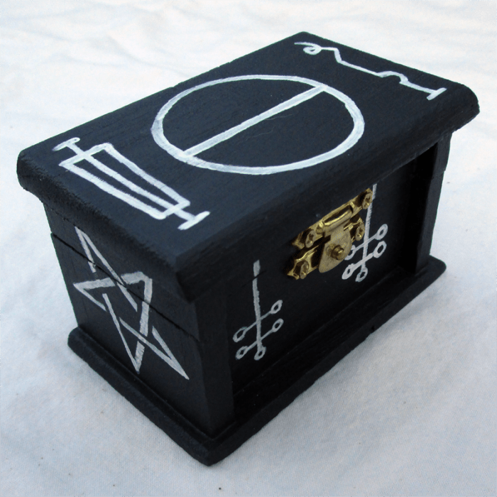 a miniature wooden box, painted black with white occult symbols.