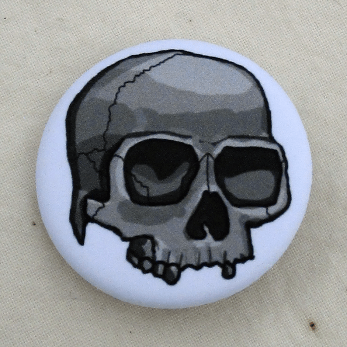A white pinback button with a grayscale skull on it