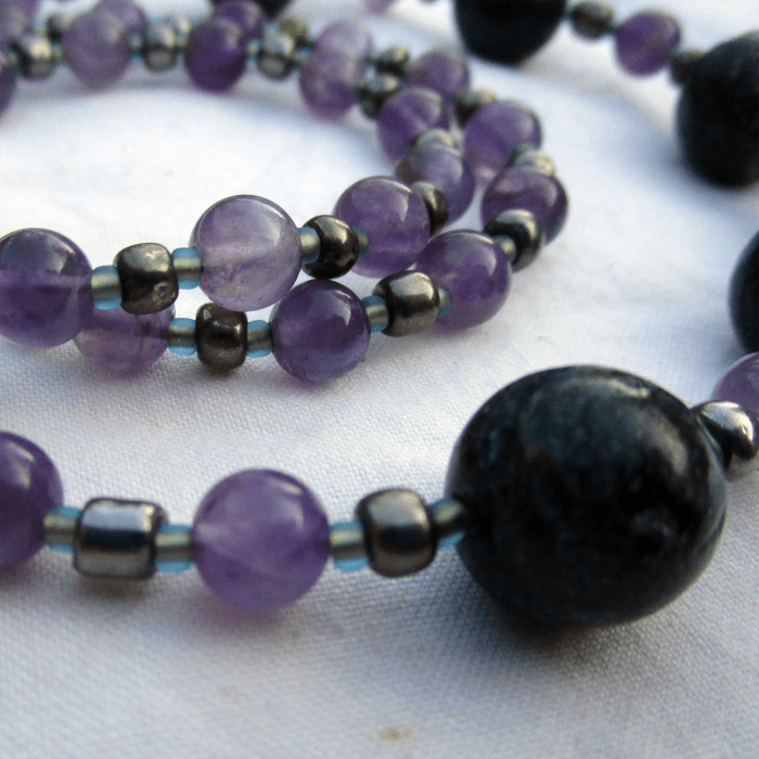 a close-up of a necklace of amethyst, glass, and seraphinite beads