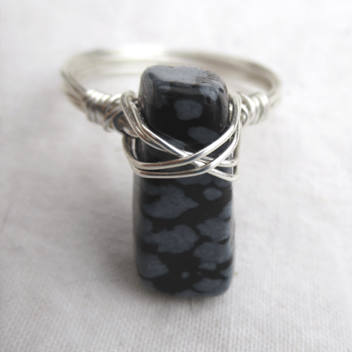 a wire wrapped ring with a snowflake obsidian slab on silver wire